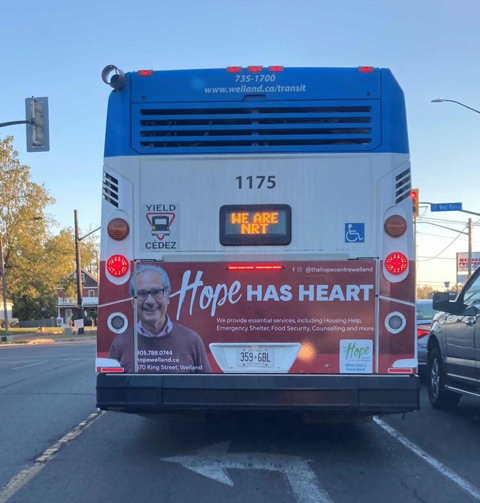 Hope has Heart advertisement  on the back of a bus with red background and senior man smiling. With contact information about The Hope Centre. 