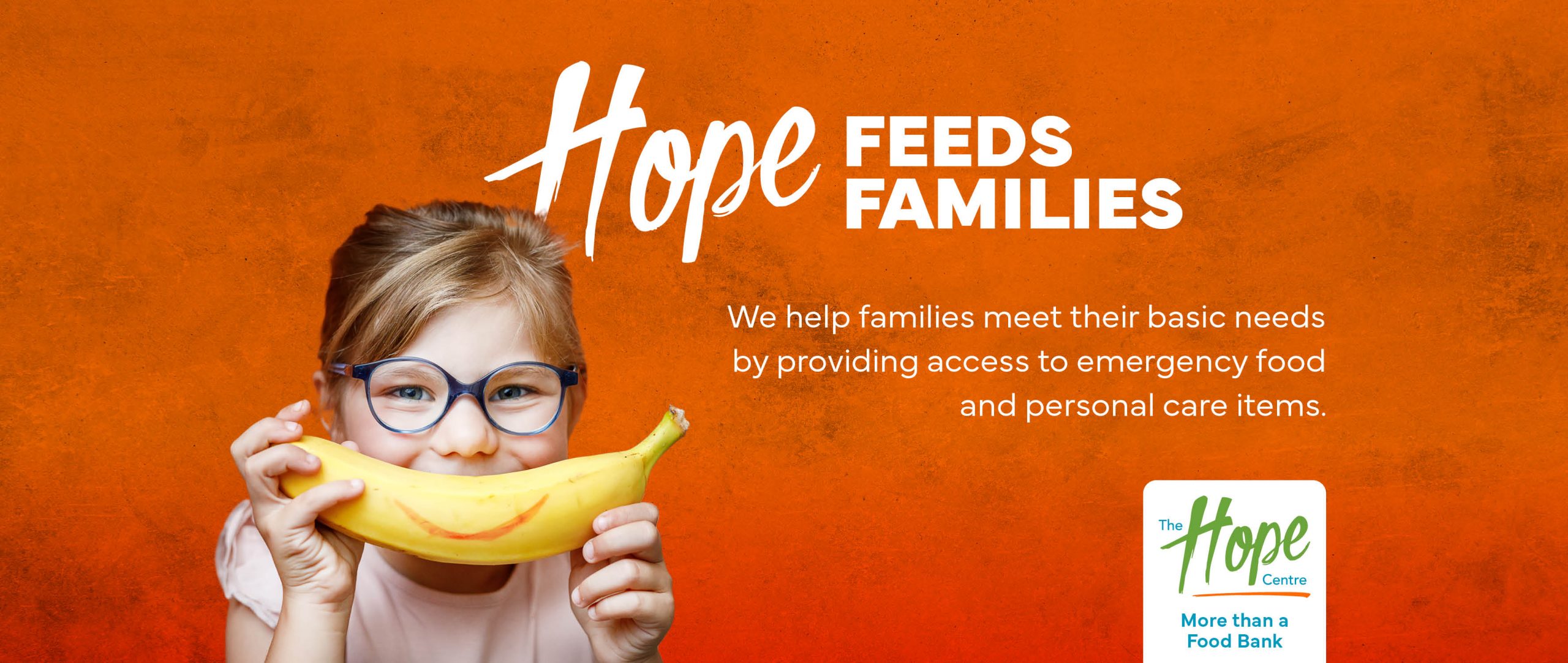 Hope Feeds Familes. We help individuals and familes meet their basic needs by providing access to nutritious food and personal care items. Photo of little girl wearing glasses holding a banana with a smile to her mouth.